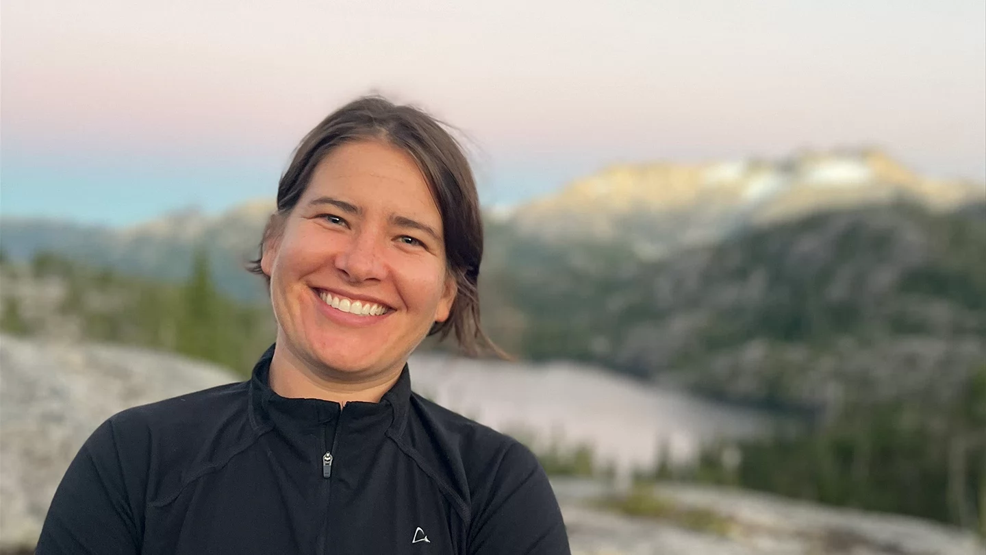 Jessica smiling with sunset-tinged mountain vista in background