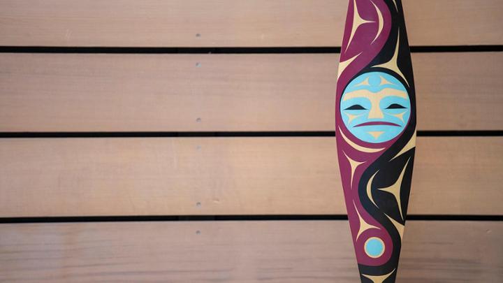 Detail photo of paddle with Coast Salish carving of a moon in light blue.
