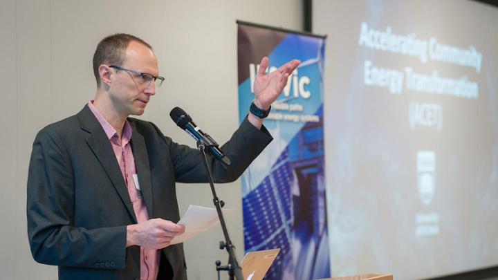 Curran Crawford standing a microphone at ACET kickoff event