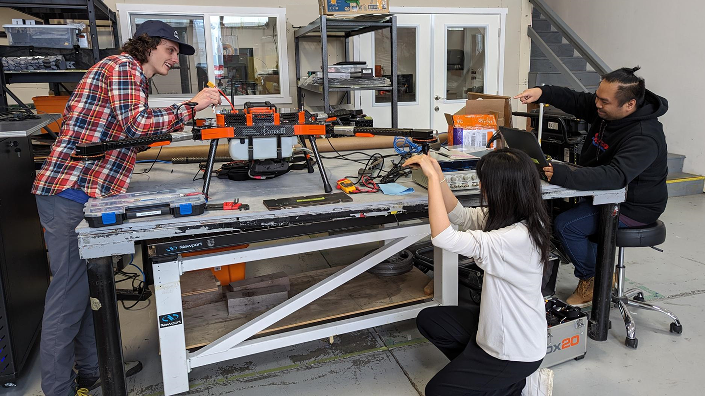 Three co-op students work on a drone
