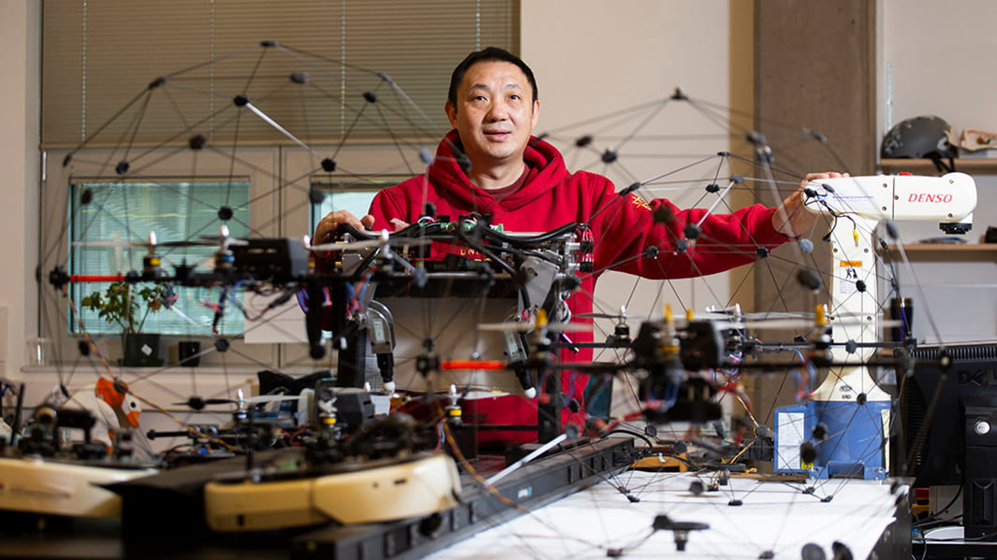 Yang Shi in his lab surrounded by drones and other tech