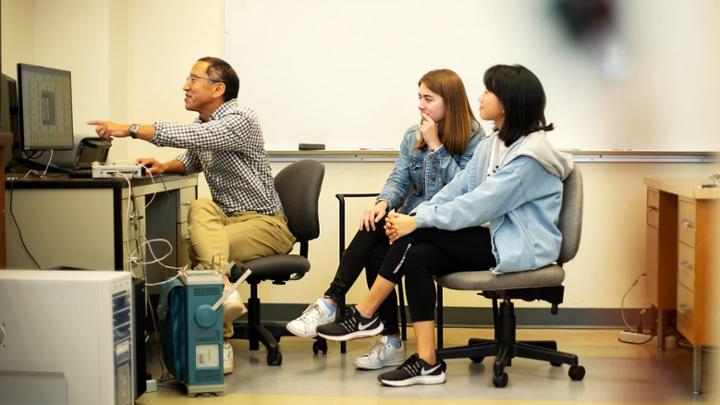 researcher showing two students something on computer screen