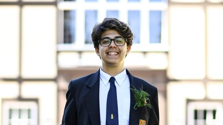 Student in formal school clothing smiling at camera outside a building