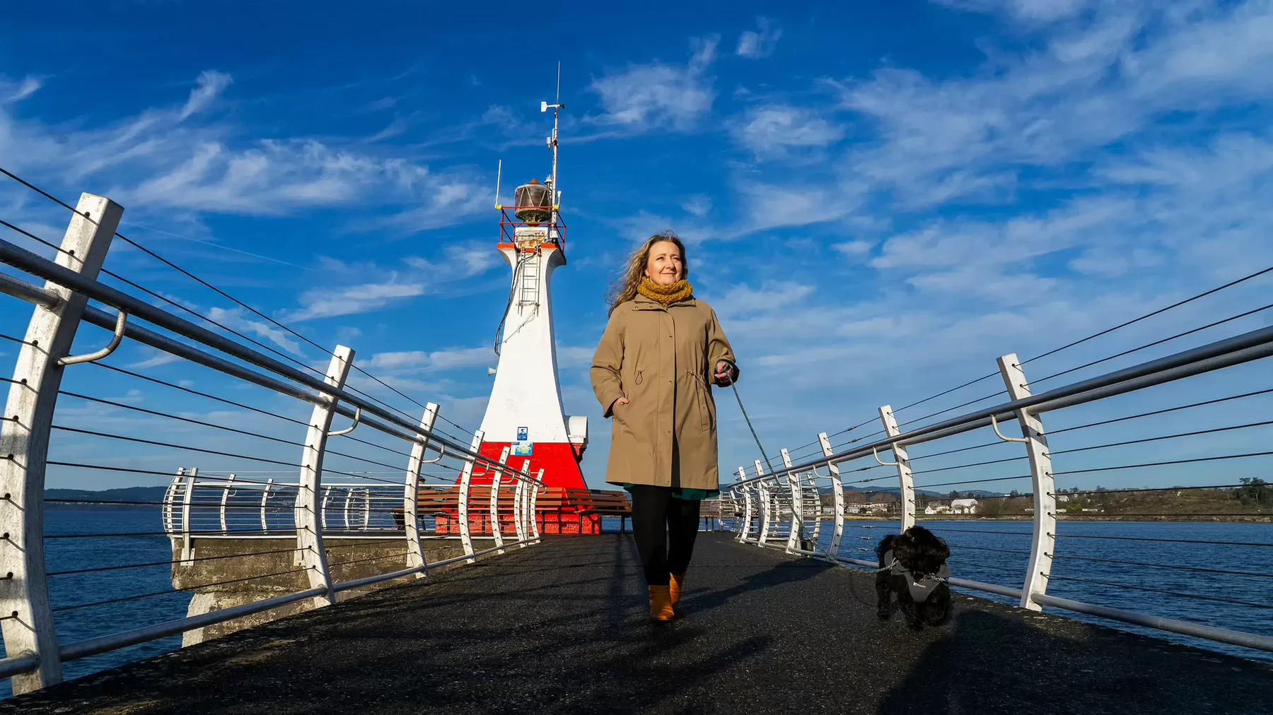 A woman walks her dog along the breakwater path in Victoria.