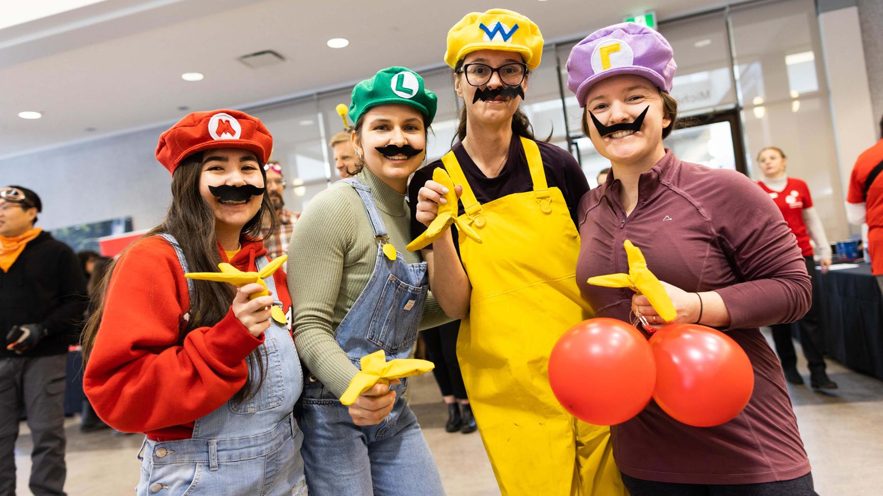 Four UVic people in costume smile at the 2022 plasma car race.