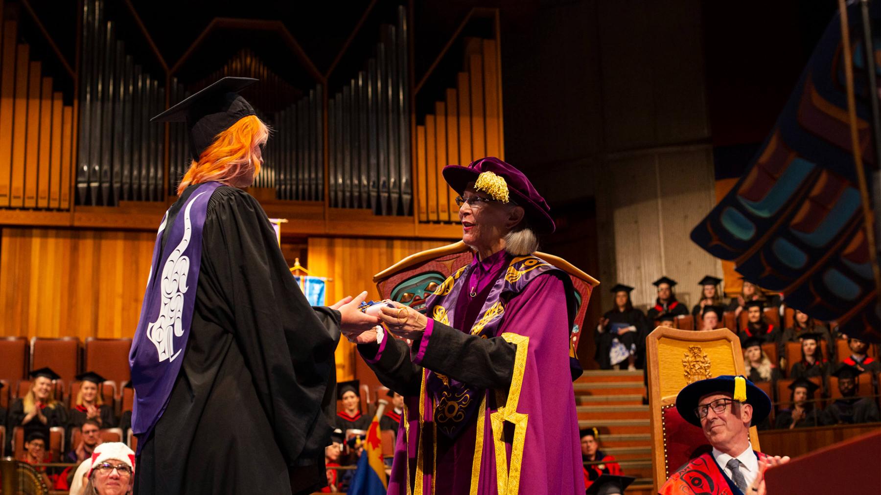A student receives their diplomas on stage at Farquhar auditorium.
