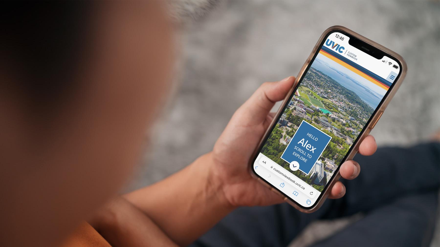A student hold a phone showing the custom viewbook main screen that they just created. 