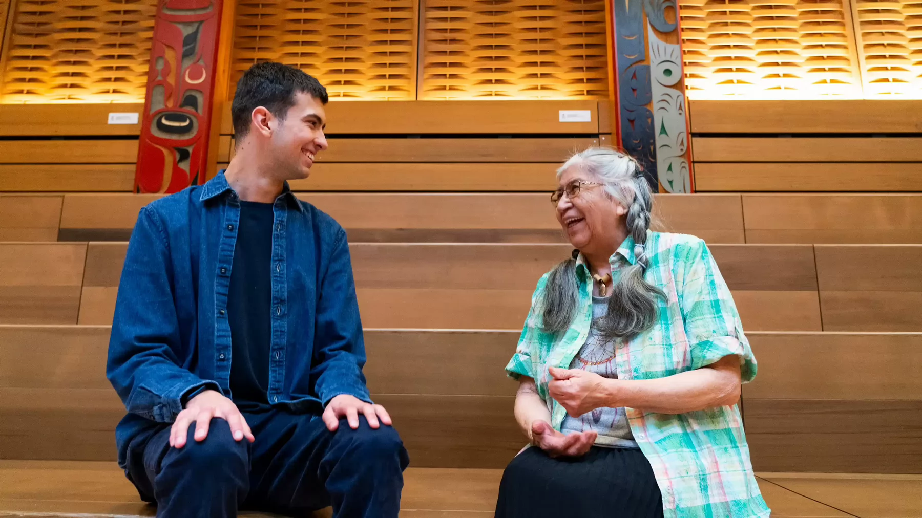 Ryder and Indigenous elder smiling in conversation in First People's House at UVic