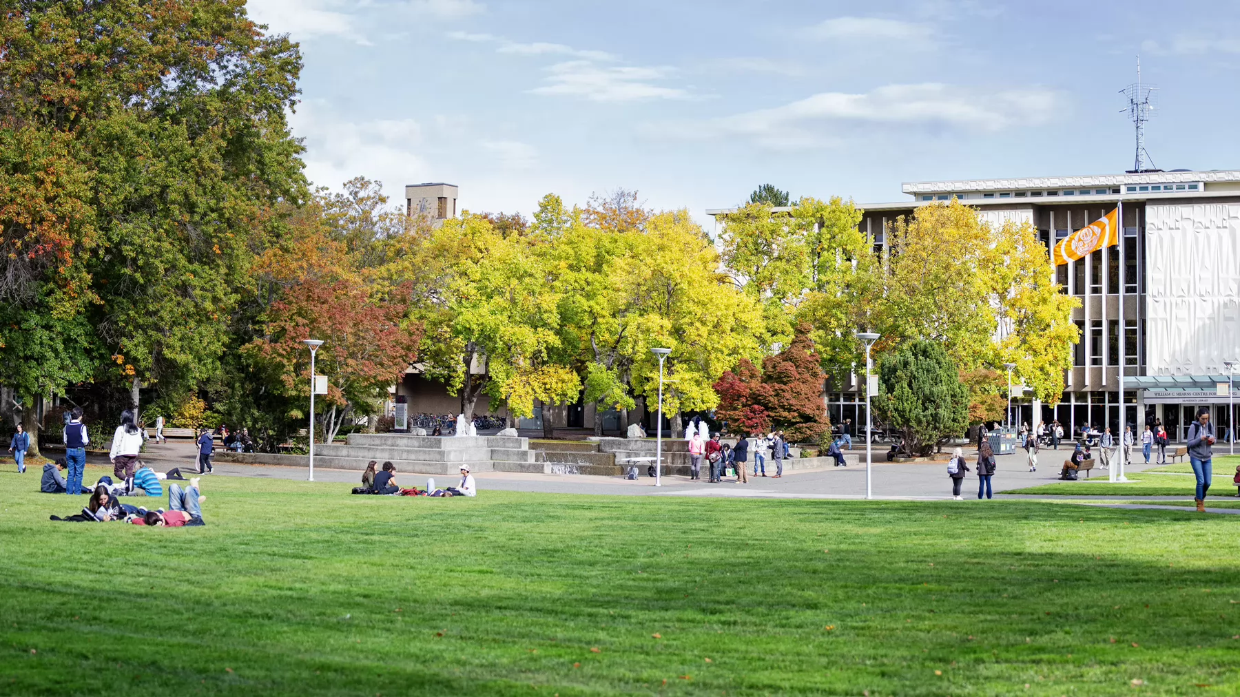 A sunny scene showing the UVic quad with students and trees. 