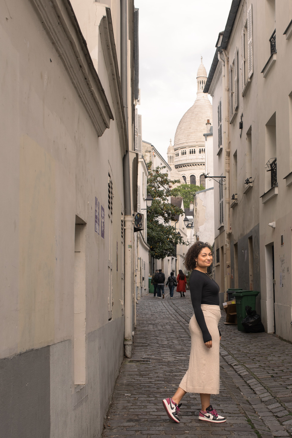A woman with curly hair walking on cobble stone street