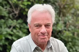 A man with white hair smiling. 