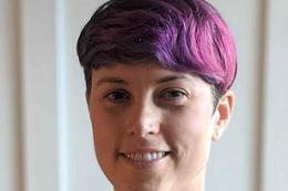 Woman with purple hair smiling.