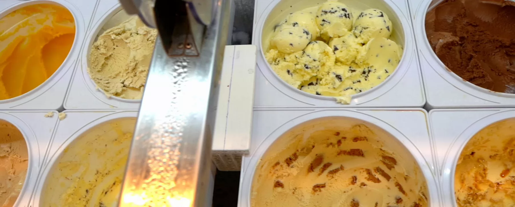 Overhead view of open ice cream containers in a freezer display case. 