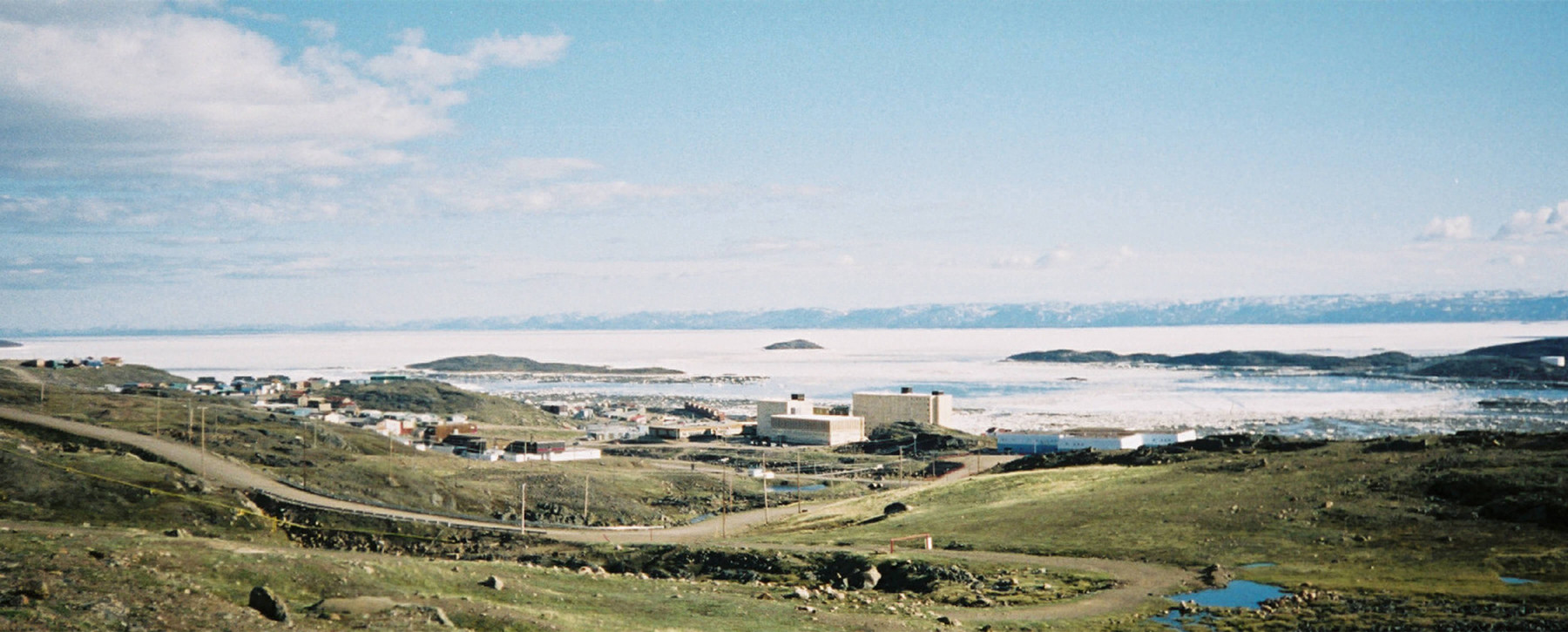Small town overlooking ice filled ocean and snowy horizon.
