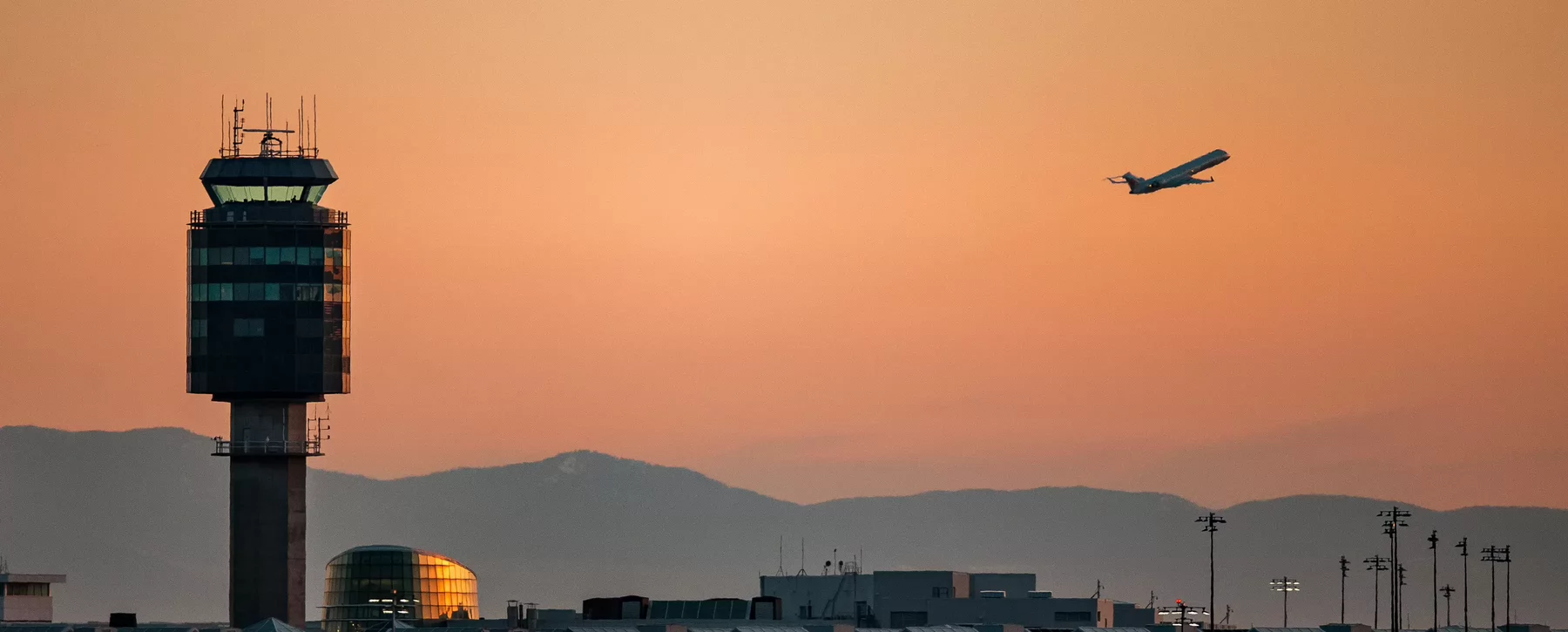 Airplane flying out of an airport at sunset. 