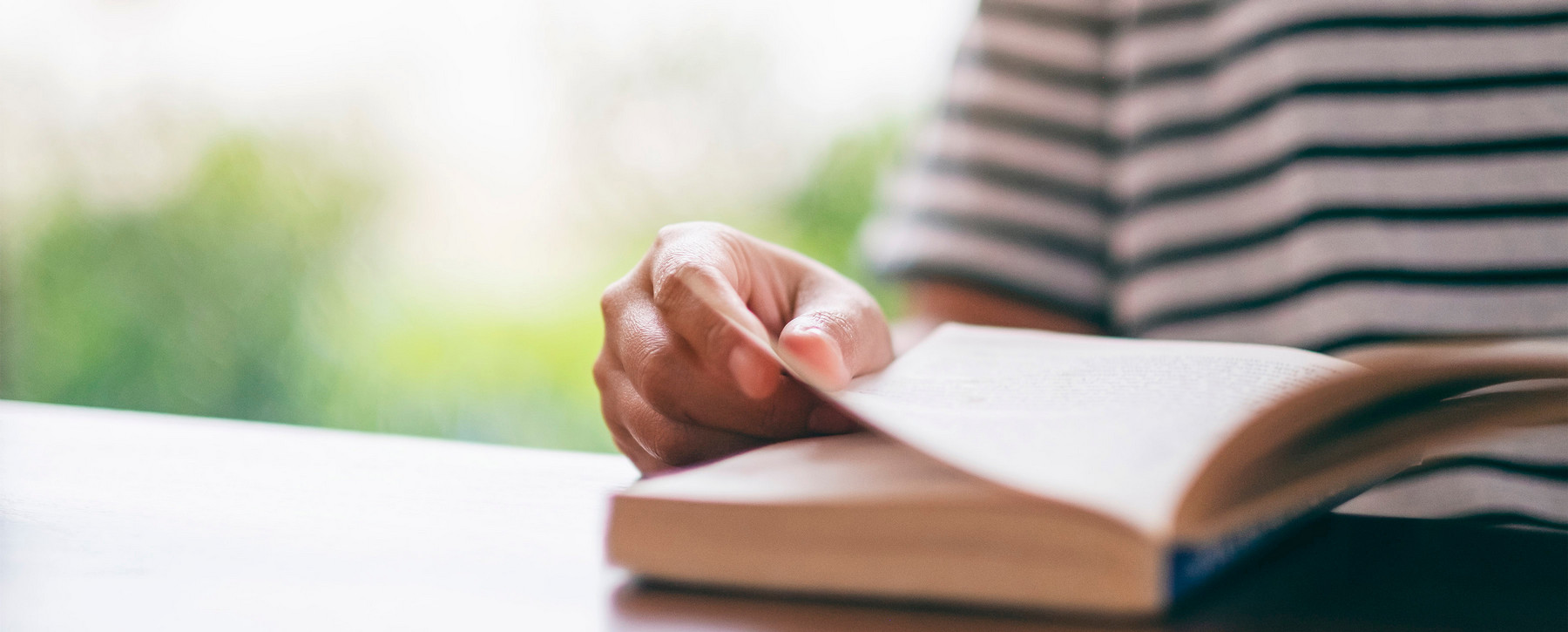 Person in striped shirt reading a book.