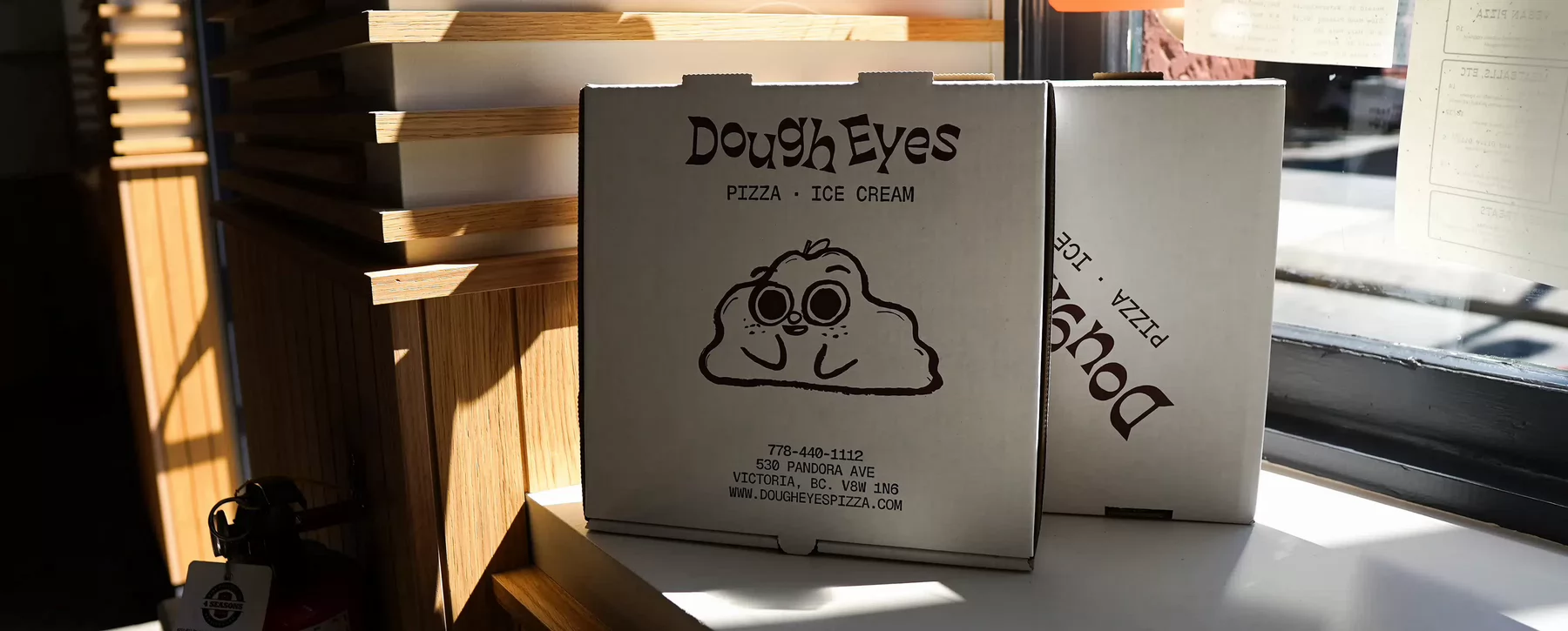 A Dough Eyes Pizza box place in front of the restaurant's widow.