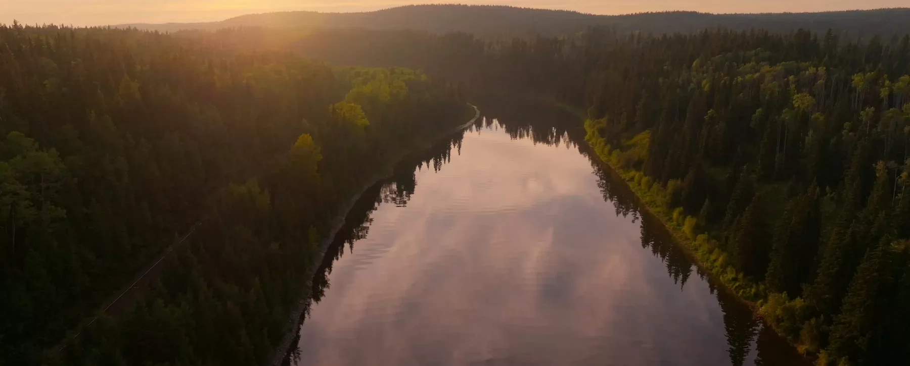 A river reflecting the sky surrounded by forest.