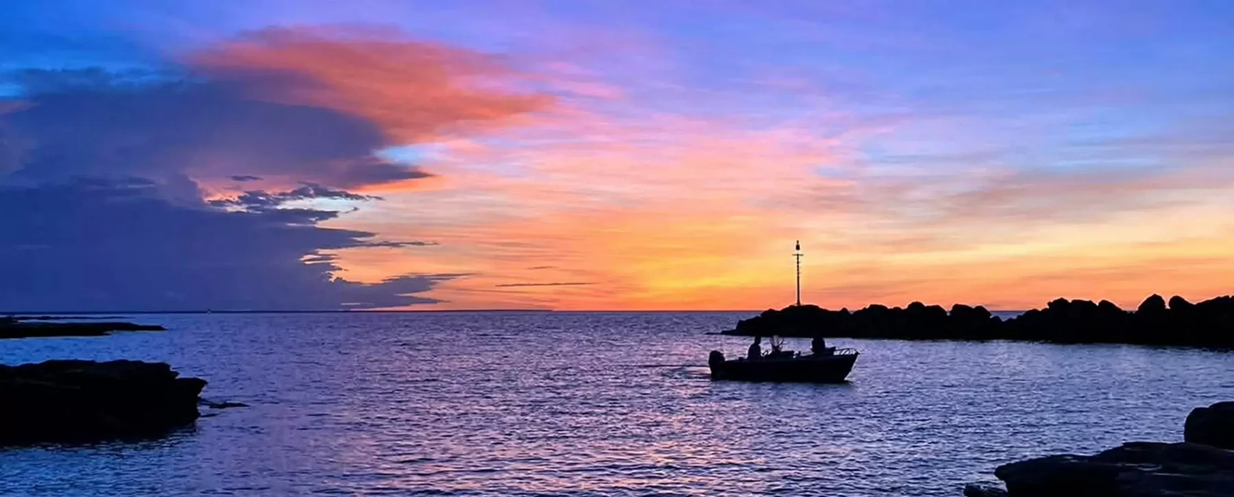 Silhouettes of boats in a harbour during sunset.