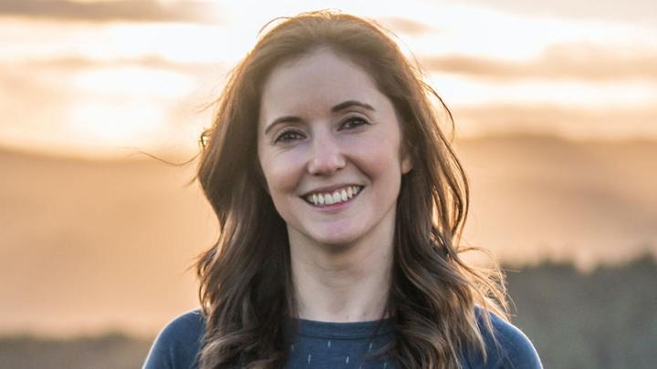 Woman smiling with sun in the background.