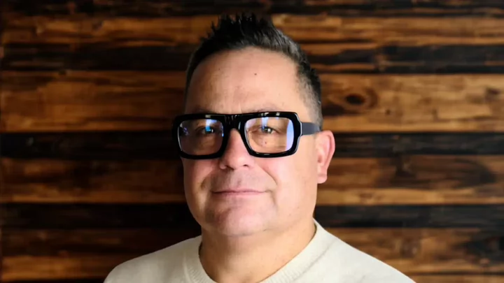 A man with thick rimmed glasses and short hair. 