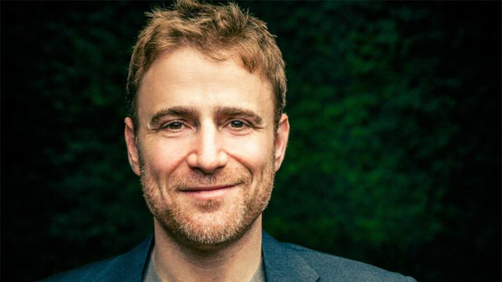 Man with stubble smiling.