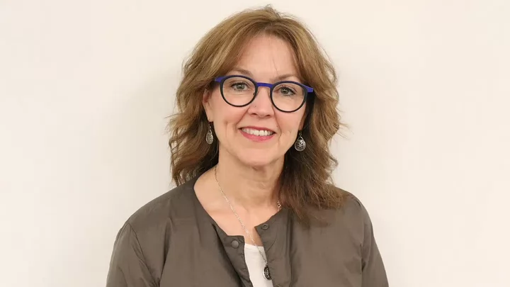 A woman with glasses smiling. 