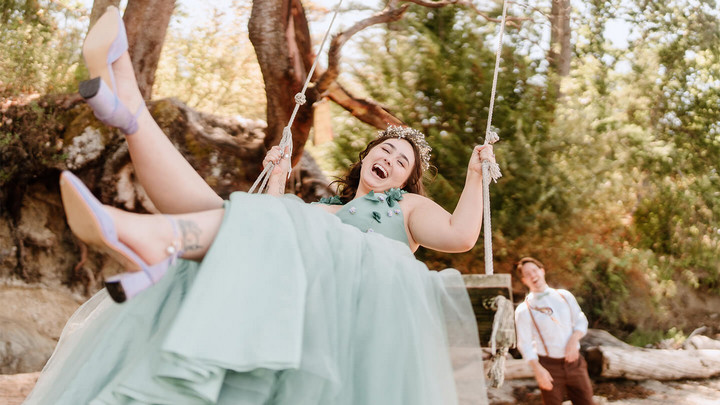 Groom pushes bride on a swing. 