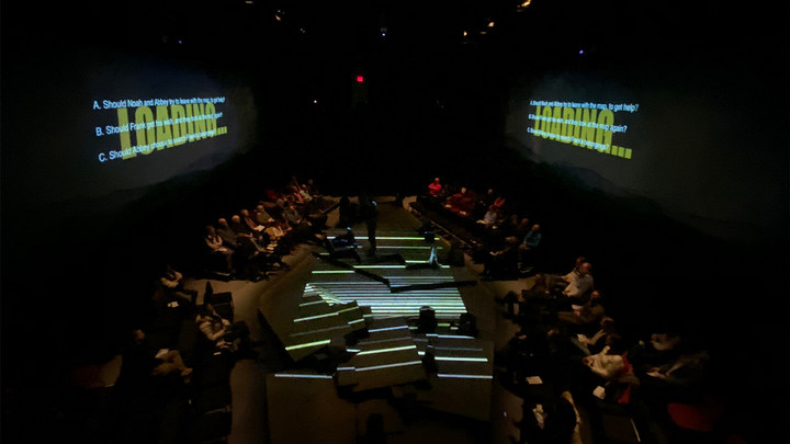Stage with audience on both sides and screens that read "Loading" above them.