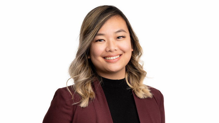 Woman with long straight hair smiling and wearing a business jacket.