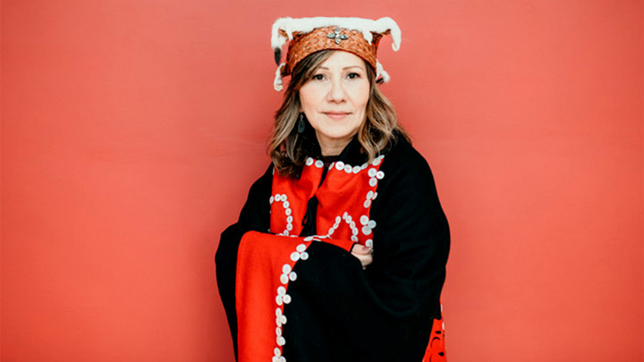 Woman wearing Indigenous hat and blanket.
