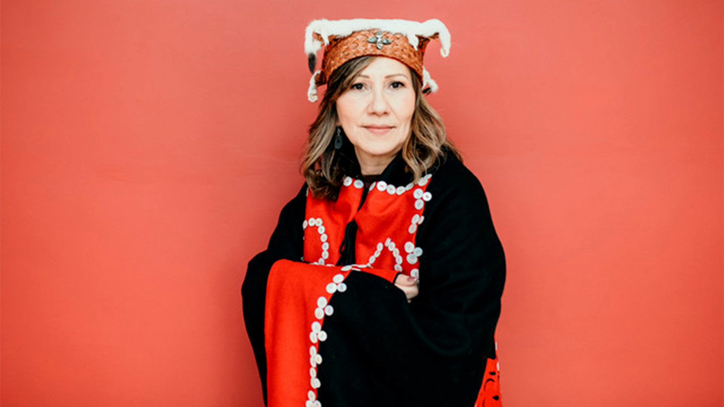 Woman wearing Indigenous hat and blanket.