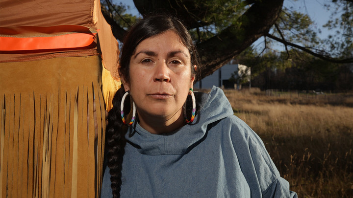 Woman wearing woven, multi-coloured earrings.
