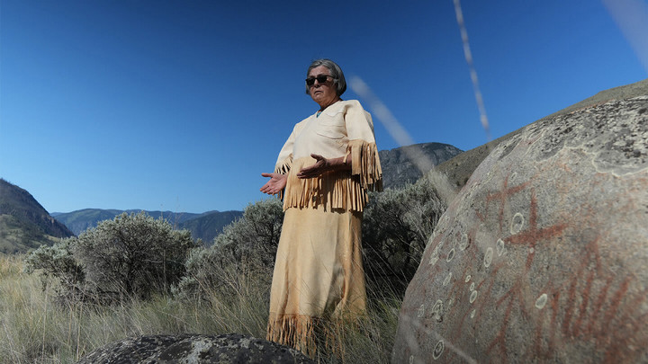 Woman standing outside with arms outstretched.