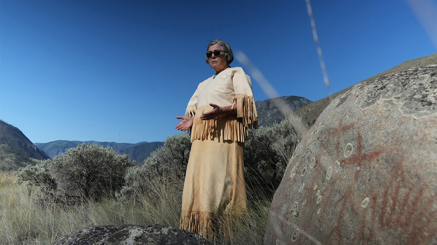 Woman standing outside with arms outstretched.