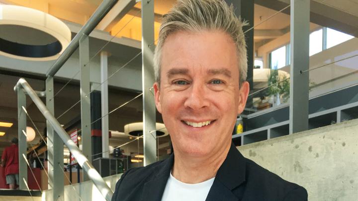 Man smiling in front of stairs and metal railings.