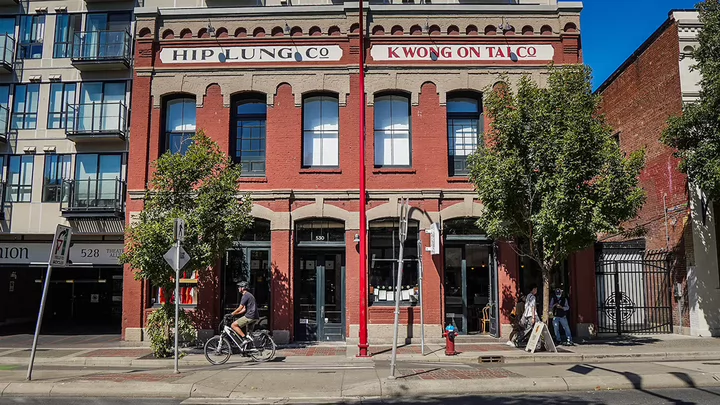 A cyclist rides by the storefront of Dough Eyes restaurant.