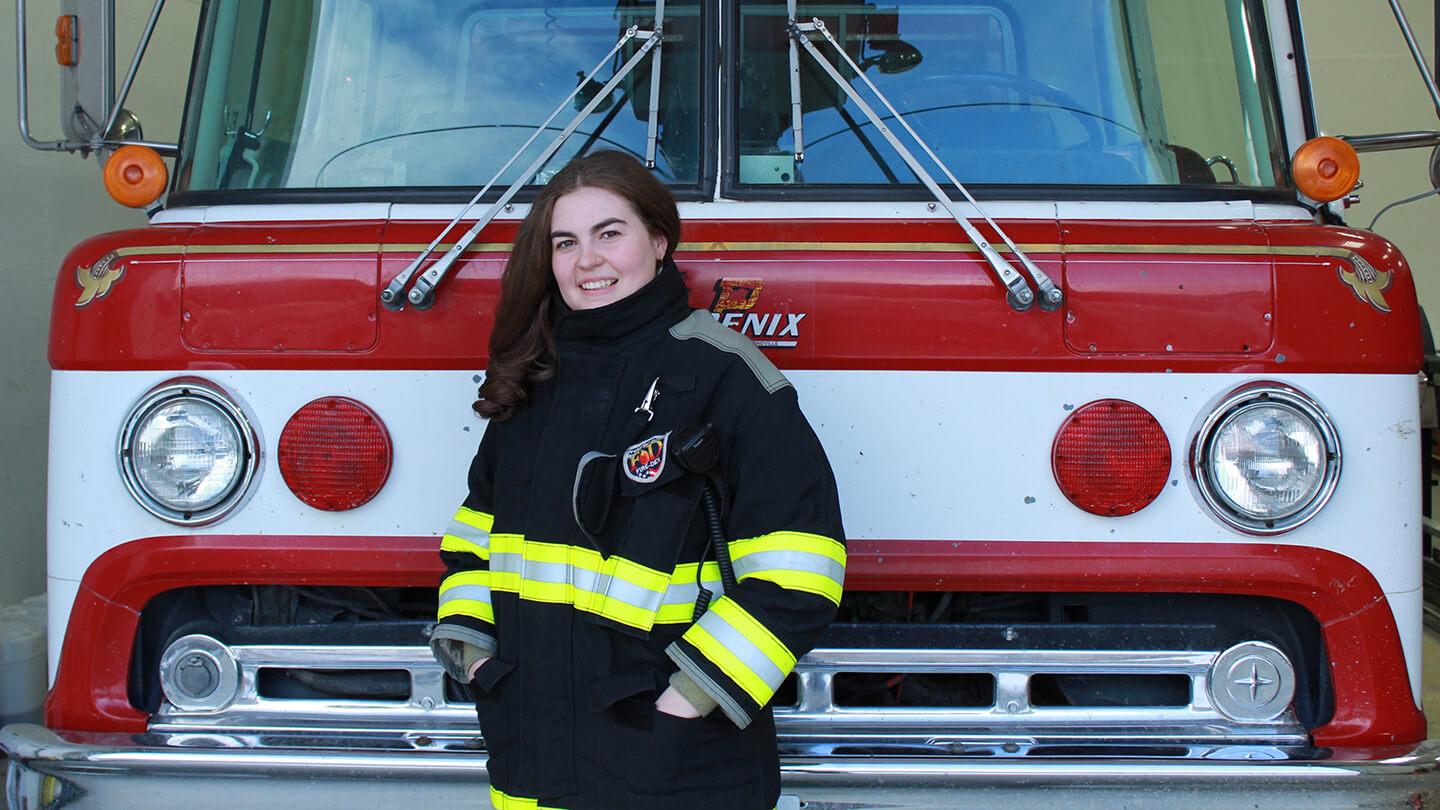 Woman smiling in front of firetruck.
