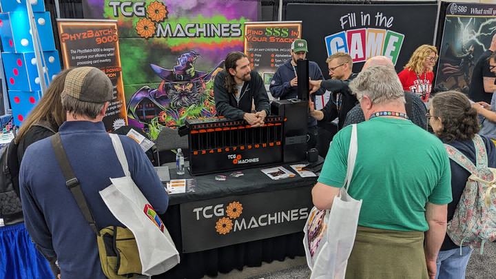 People gathered around a tradeshow booth for TCG Machines.