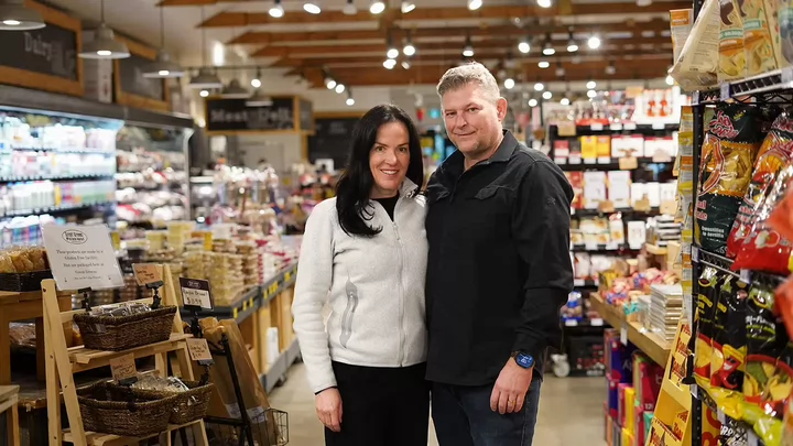 A man and woman standing side by side in a grocery store. 