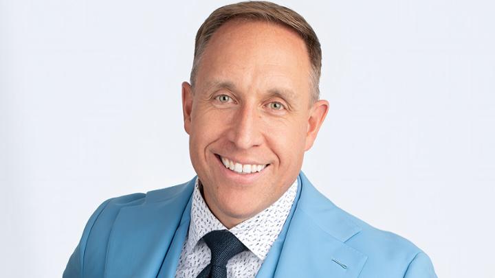 Man in blue suit smiling.