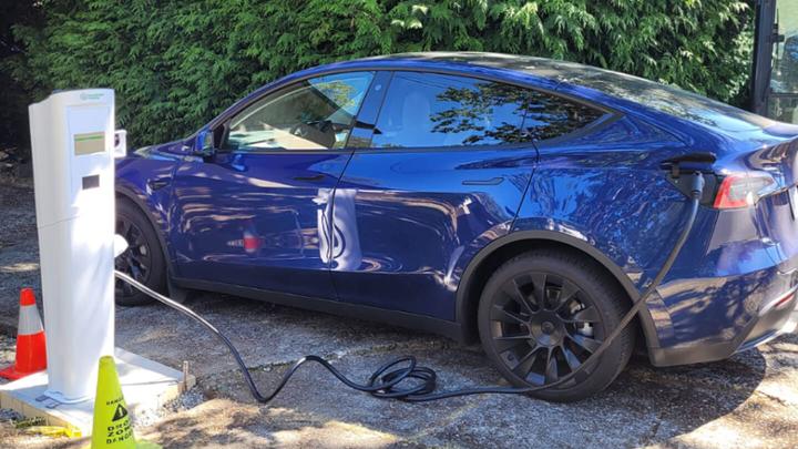 Blue electric car hooked up to a charging station.