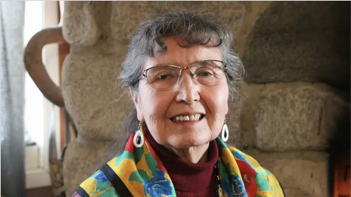 Woman smiling wearing glasses and colourful scarf.