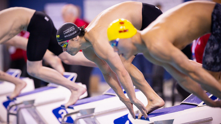 Man in swim cap and goggles about to start race.