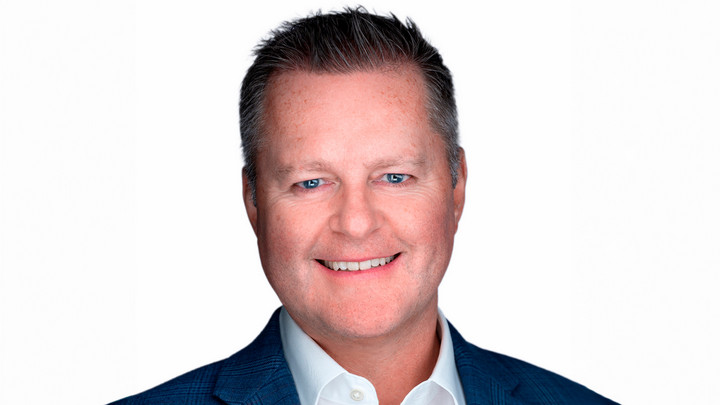 Man in button up shirt and jacket smiling. 