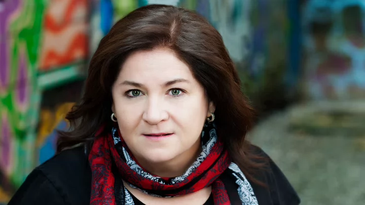 A woman standing in front of graffiti. 