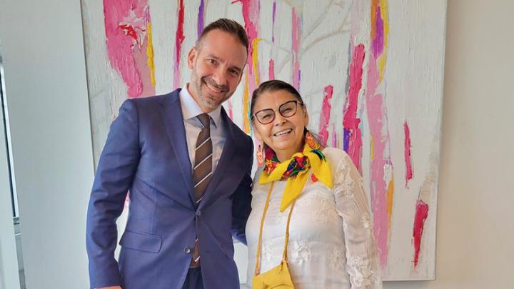 Man and woman smiling in front of painting.