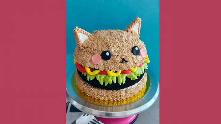 A cake decorated to look like a cat crossed with a hamburger.