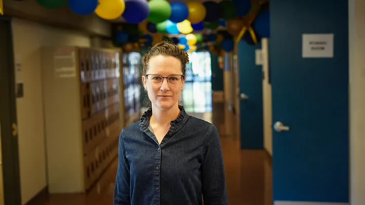 Robing volunteer Mandy Pearce standing in a hallway with balloons affixed to the ceiling. 