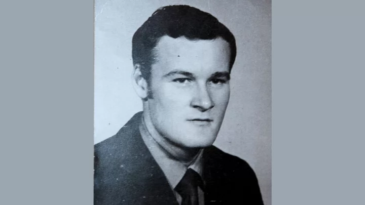 A black and white photo of a young man with short hair wearing a jacket, dress shirt and tie. 